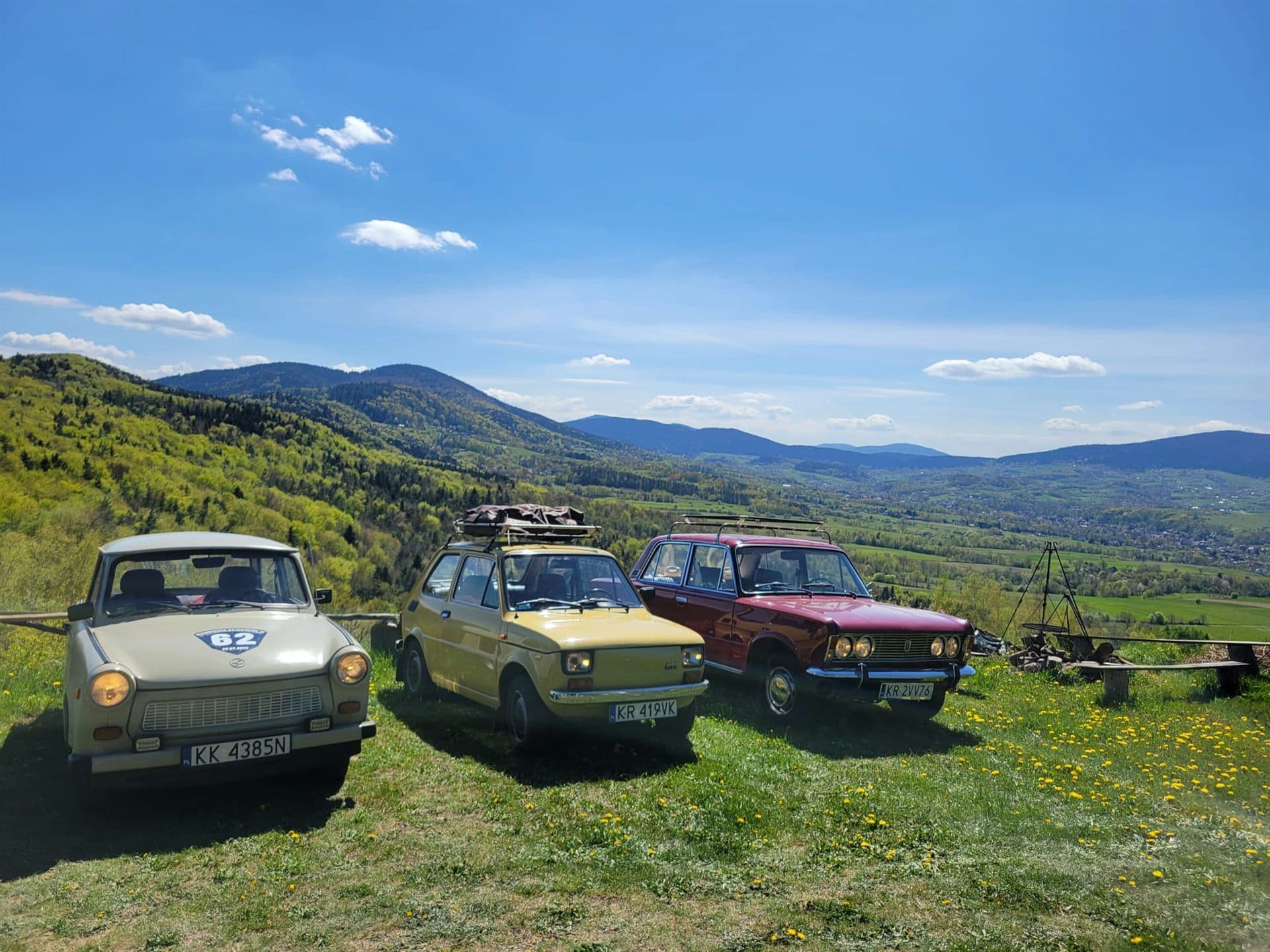 Zabytkowe fiaty na łące z widokiem na Beskid Wyspowy